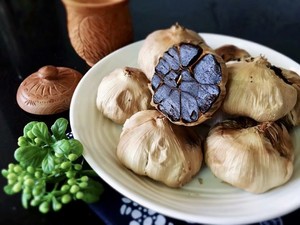 Half-cut and whole black garlics in dish