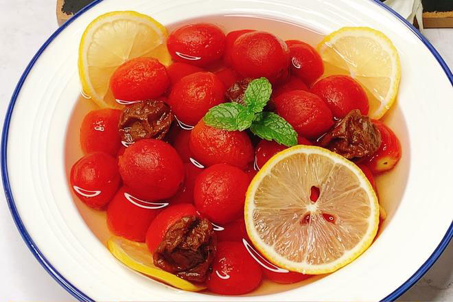 Chilled Sweet and sour Cherry Tomatoes, some cherry tomatoes and lemon pieces in a white bowl 