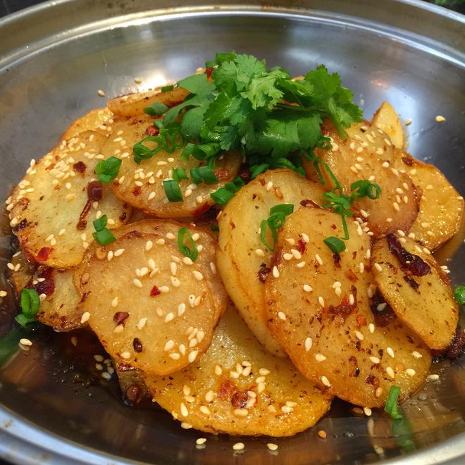 Griddle potato chips in a metal plate with some chopped green onions