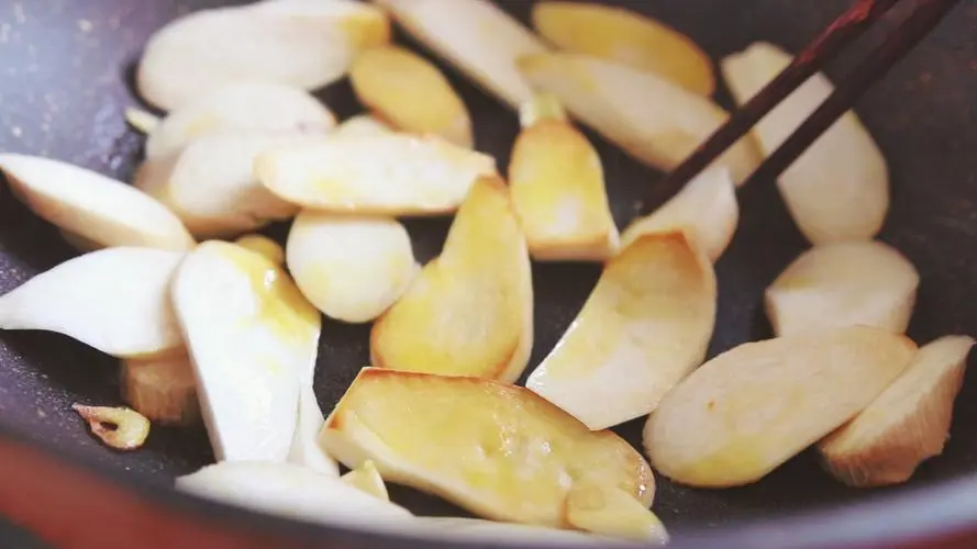 pan fry King oyster mushroom slices in a pan with chopsticks