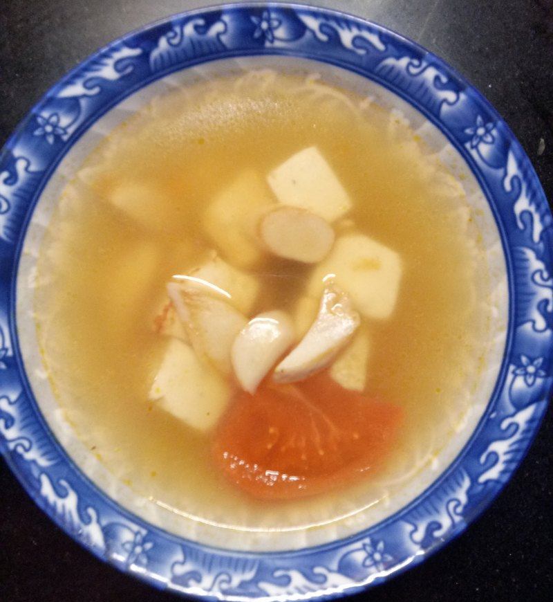 a bowl of king oyster mushroom soup with 1 piece of tomato