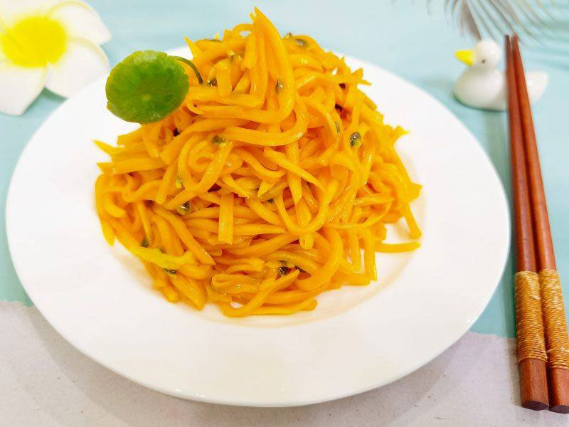 yellow pumpkin salad strips on a plate with a pair of chopsticks