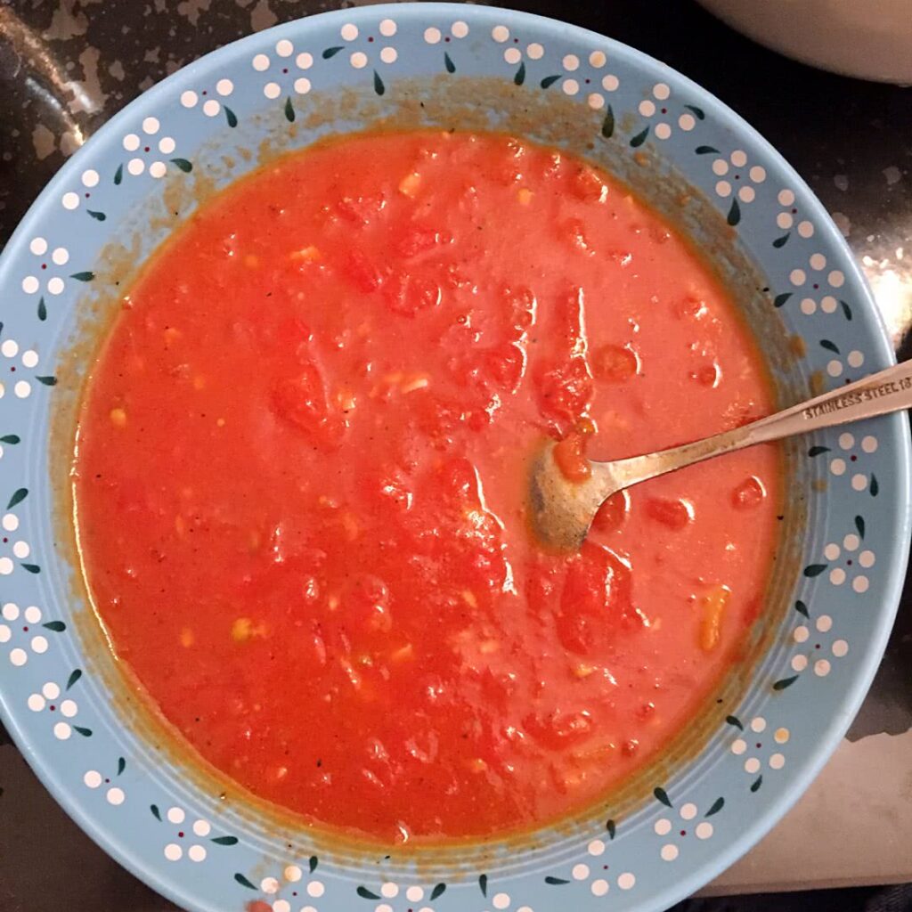 red tomato soup in a blue bowl with a spoon